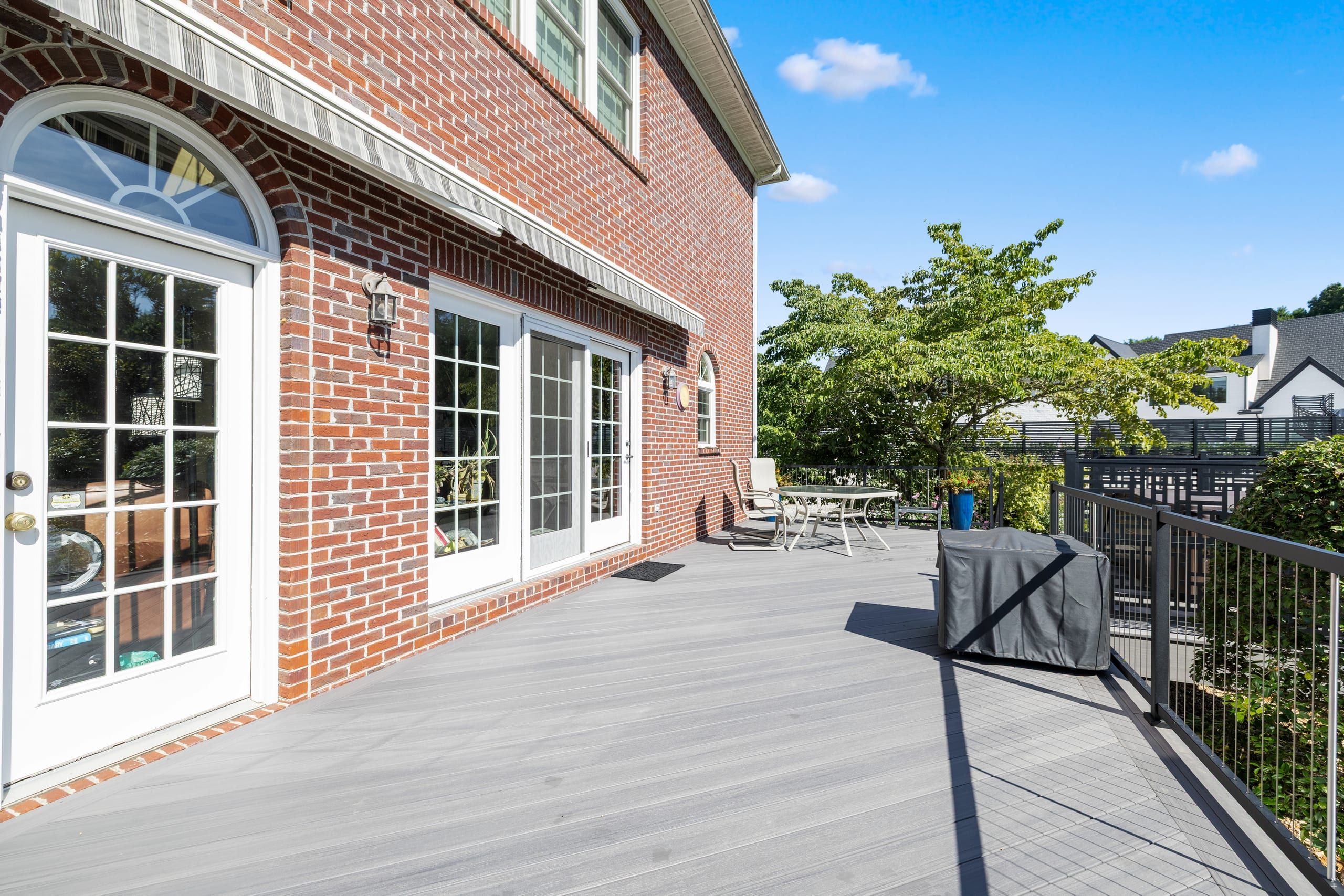 Wilshire composite deck outside the home's French doors, with gray decking and black vertical cable railing