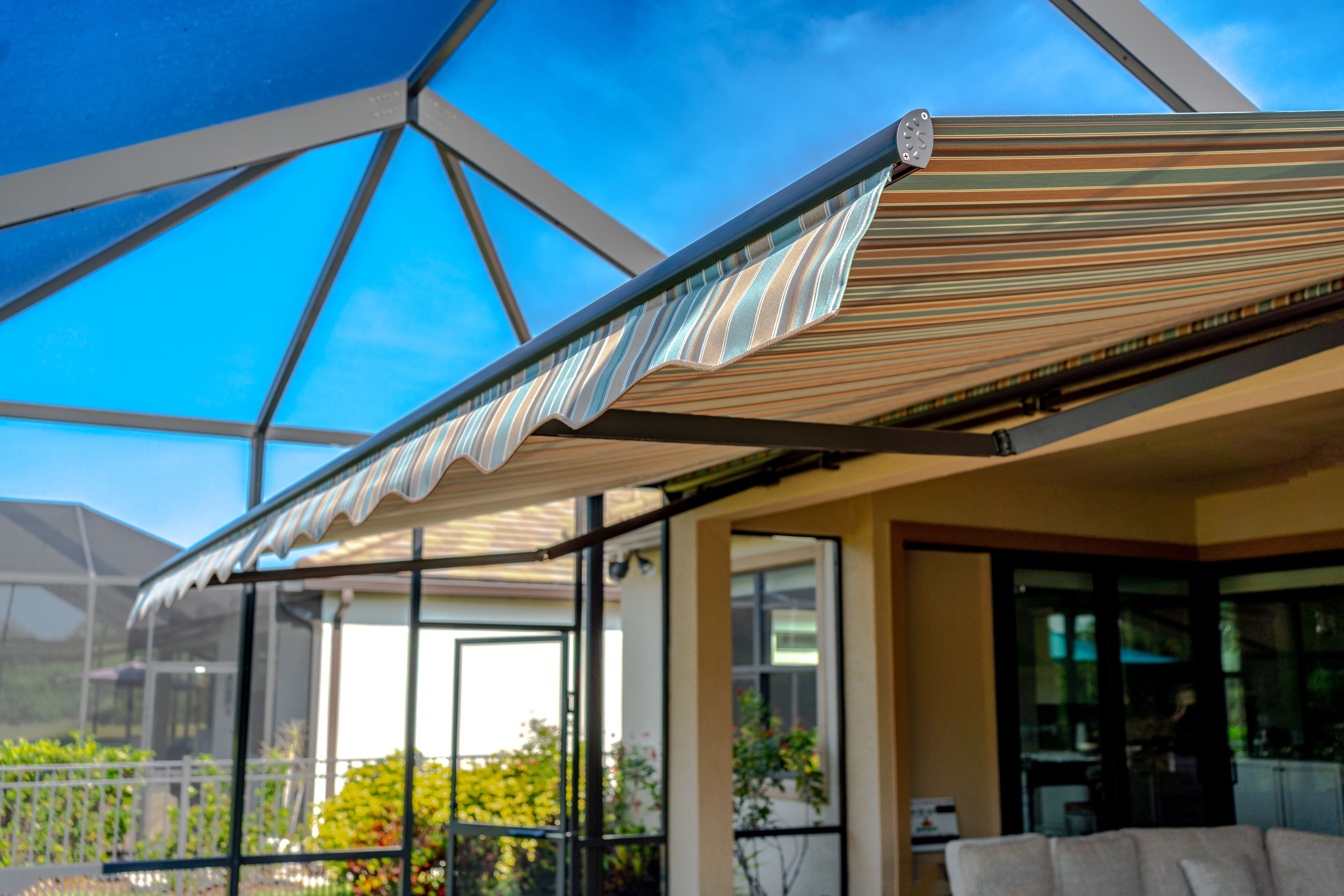 Striped retractable awning extended over a screened lanai and pool enclosure